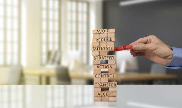 tessere di legno a torre che rischiano di cadere con la tessera rossa del risk management